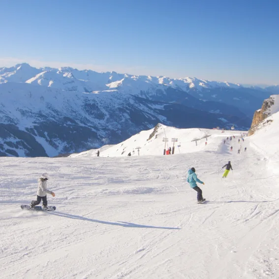 Riders spread across a wide open slope high above the valley.