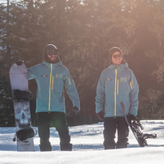 Two snowboard instructors standing with their boards in the low winter sun.