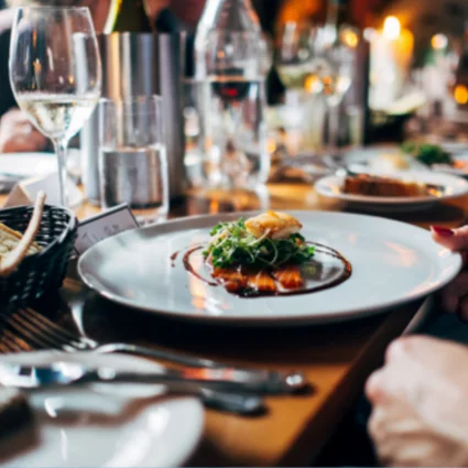 A plated dish on a candlelit restaurant table with wine glasses.