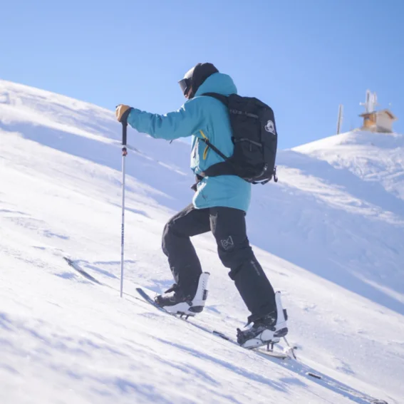 A splitboarder skinning up a ridge towards a mountain-top station.